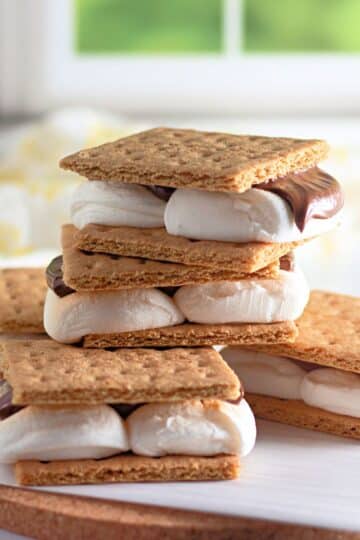 A stack of smores on parchment paper in front of a window.