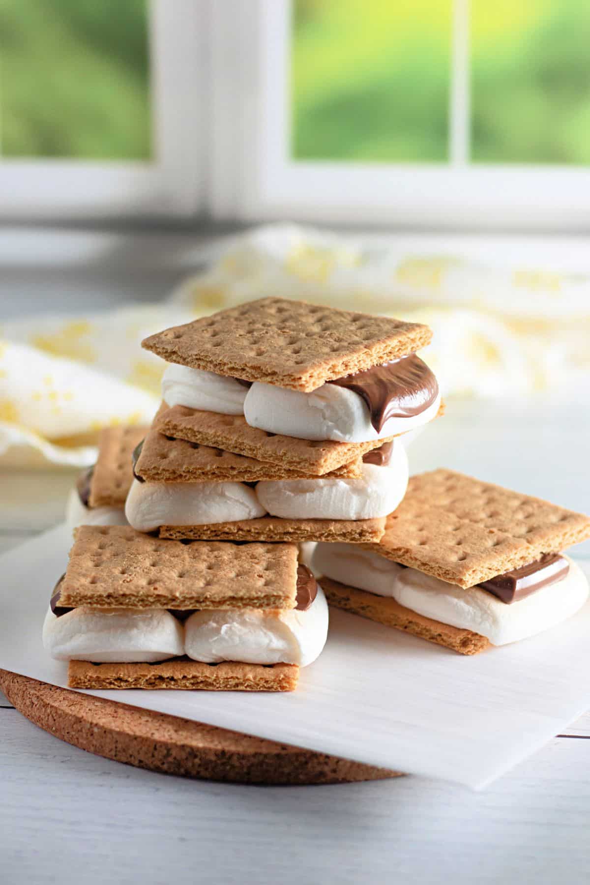 A stack of smores on parchment paper in front of a window. 