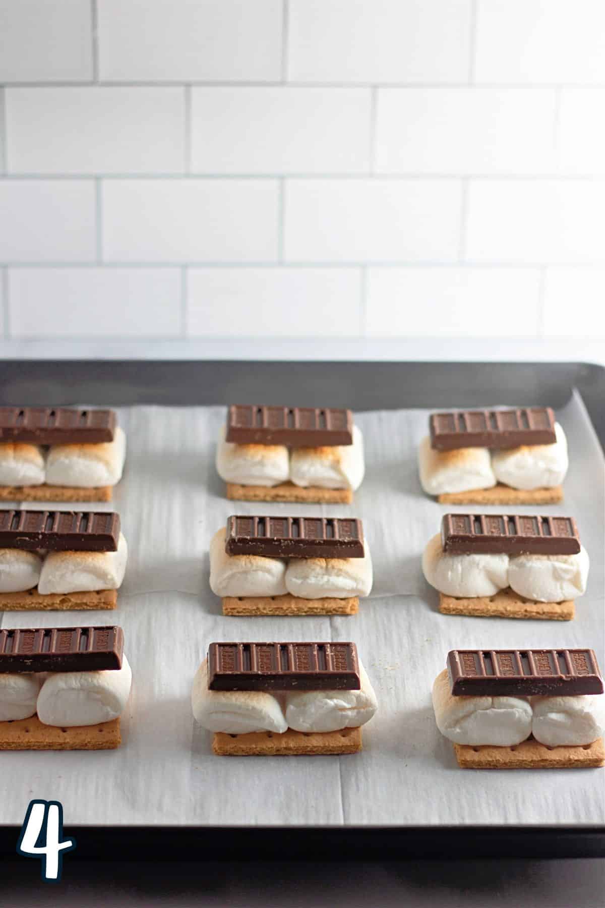 Chocolate bars on top of toasted marshmallows on a baking sheet. 