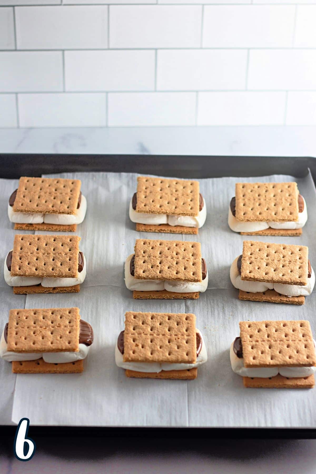 Several rows of smores on a baking sheet.