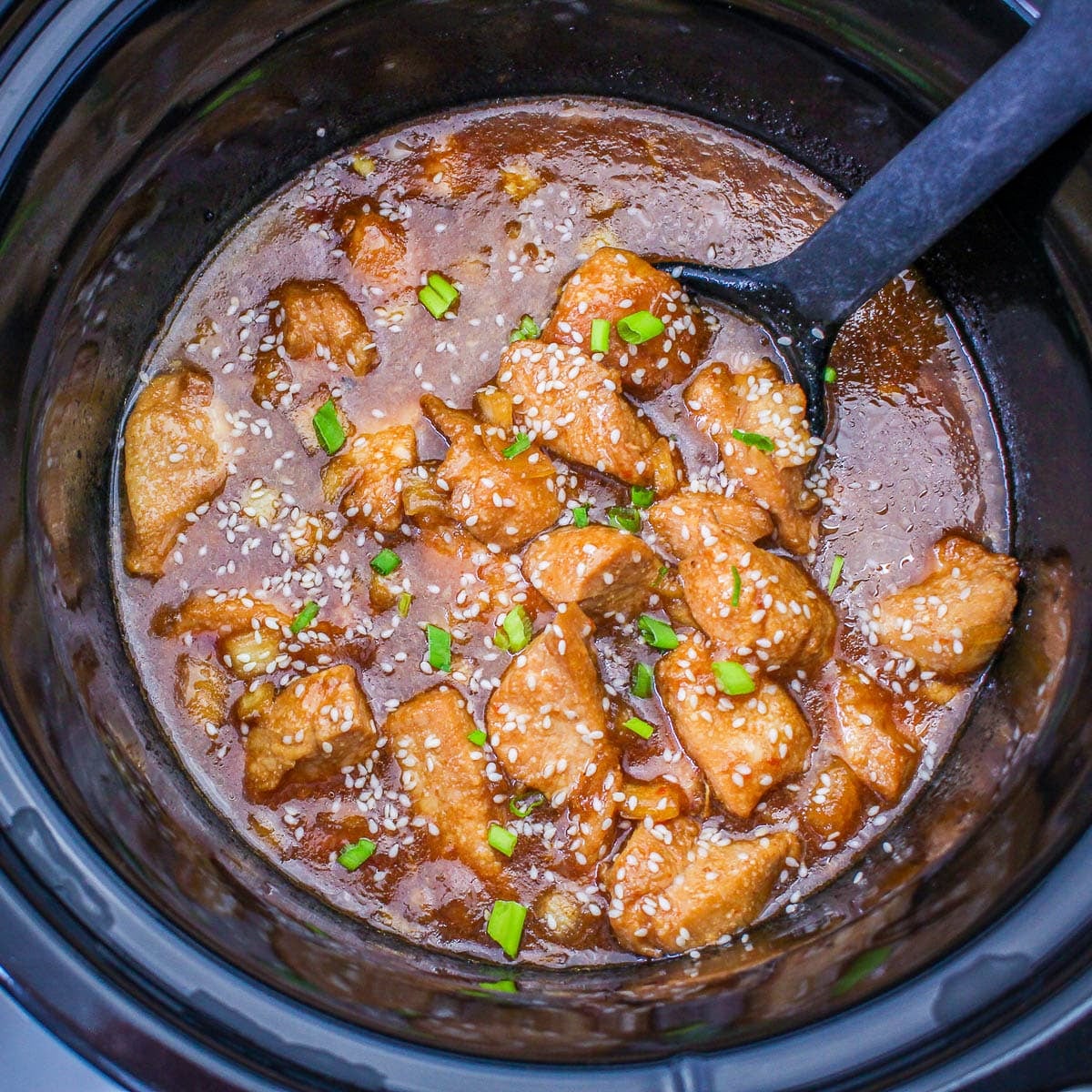 Slow Cooker Sesame Chicken features chunks of chicken in a rich brown sauce, sprinkled with sesame seeds and chopped green onions, all made effortlessly in your slow cooker.