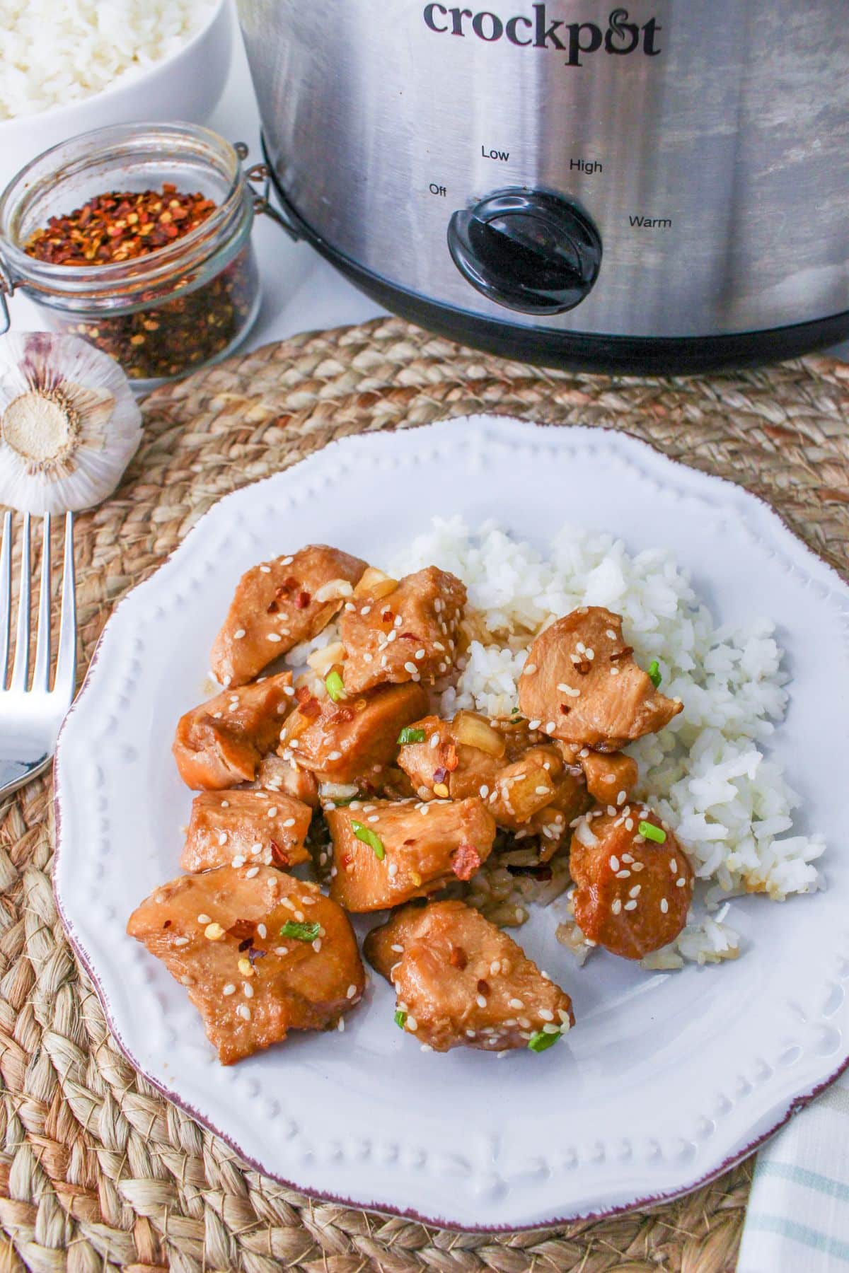 Sesame chicken on a  white plate with rice. 