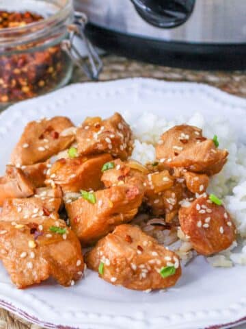 Sesame chicken with rice on a white plate.