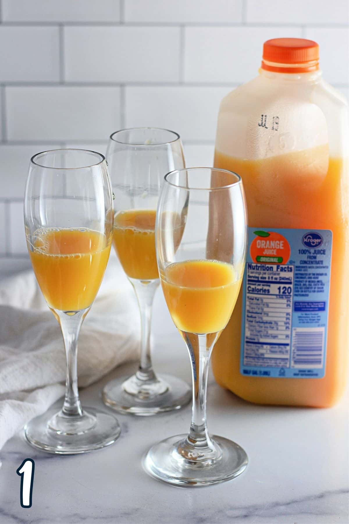 Champagne glasses filled one third full of orange juice. 