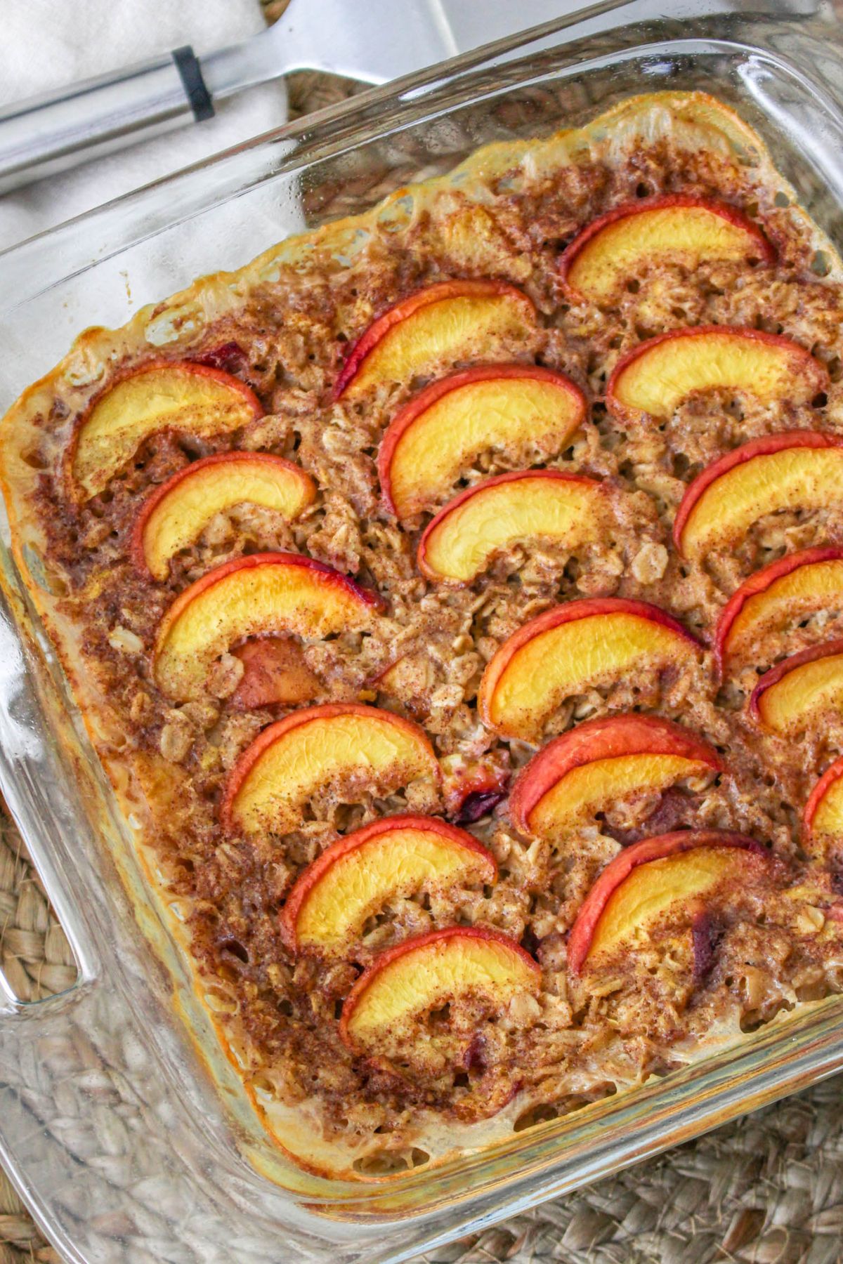 A baking dish with peach oatmeal topped with sliced peaches. .