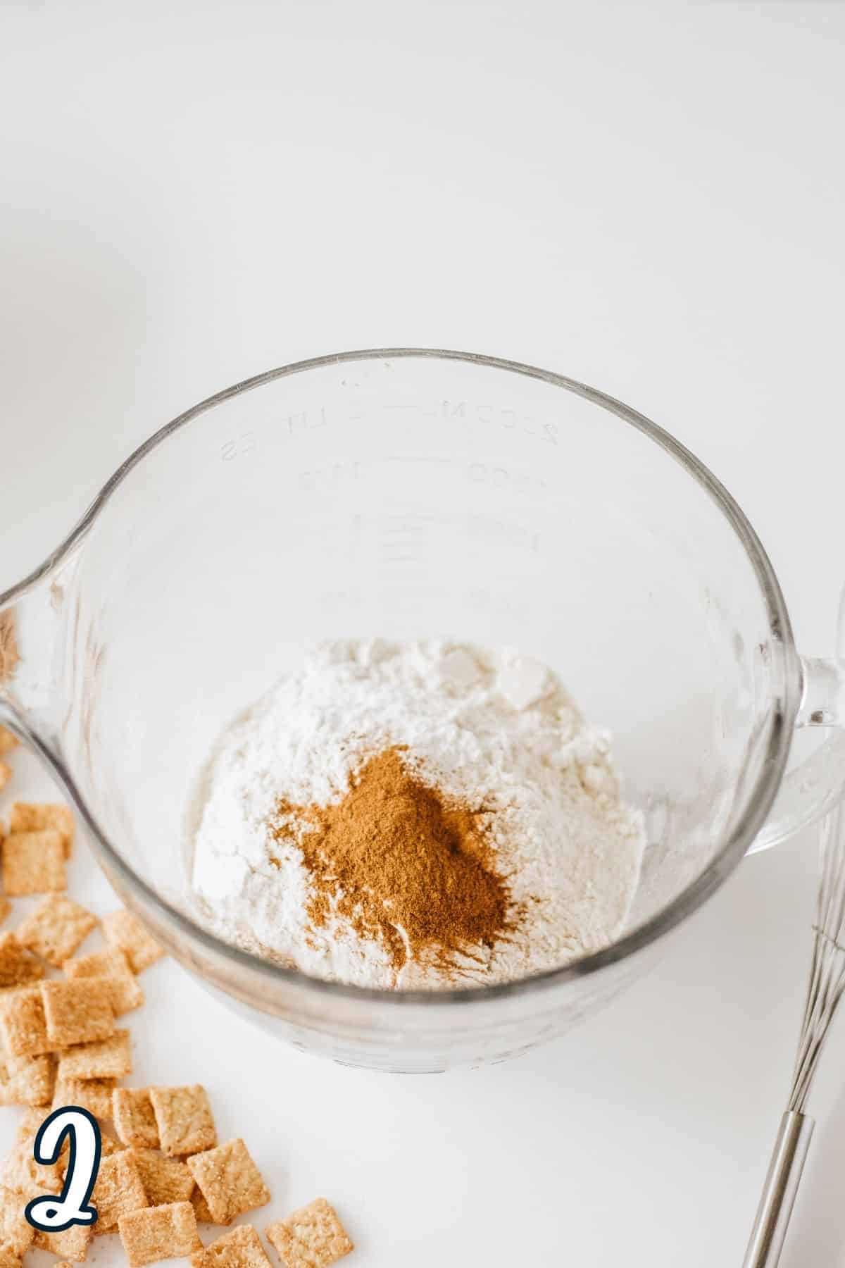 Flour, baking powder, baking soda, and cinnamon in a large glass mixing bowl. 