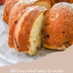 A sliced Peach Bundt Cake dusted with powdered sugar rests on a marble surface. Text: "Peach Bundt Cake".