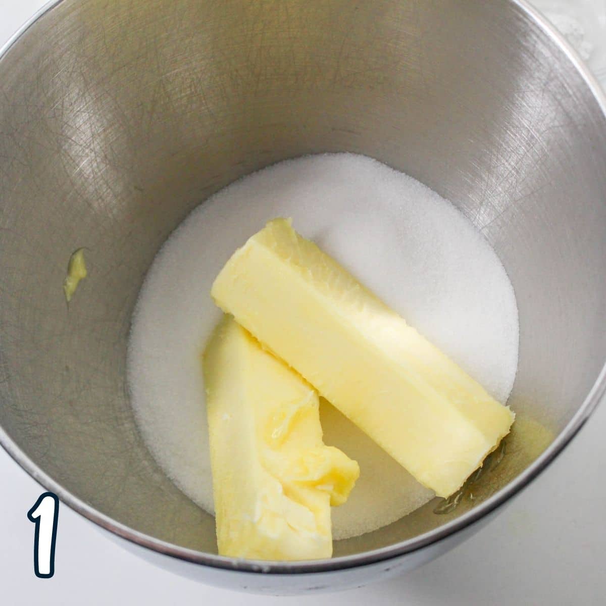 Butter and sugar in a metal mixing bowl. 