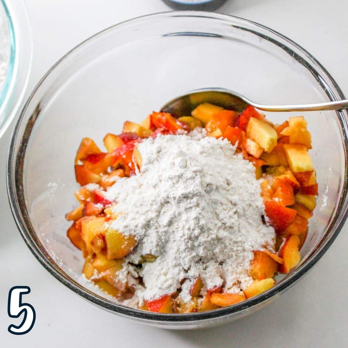 Diced peaches with flour in a mixing bowl. 