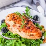 A baked chicken breast with blackberry glaze on a bed of lettuce.