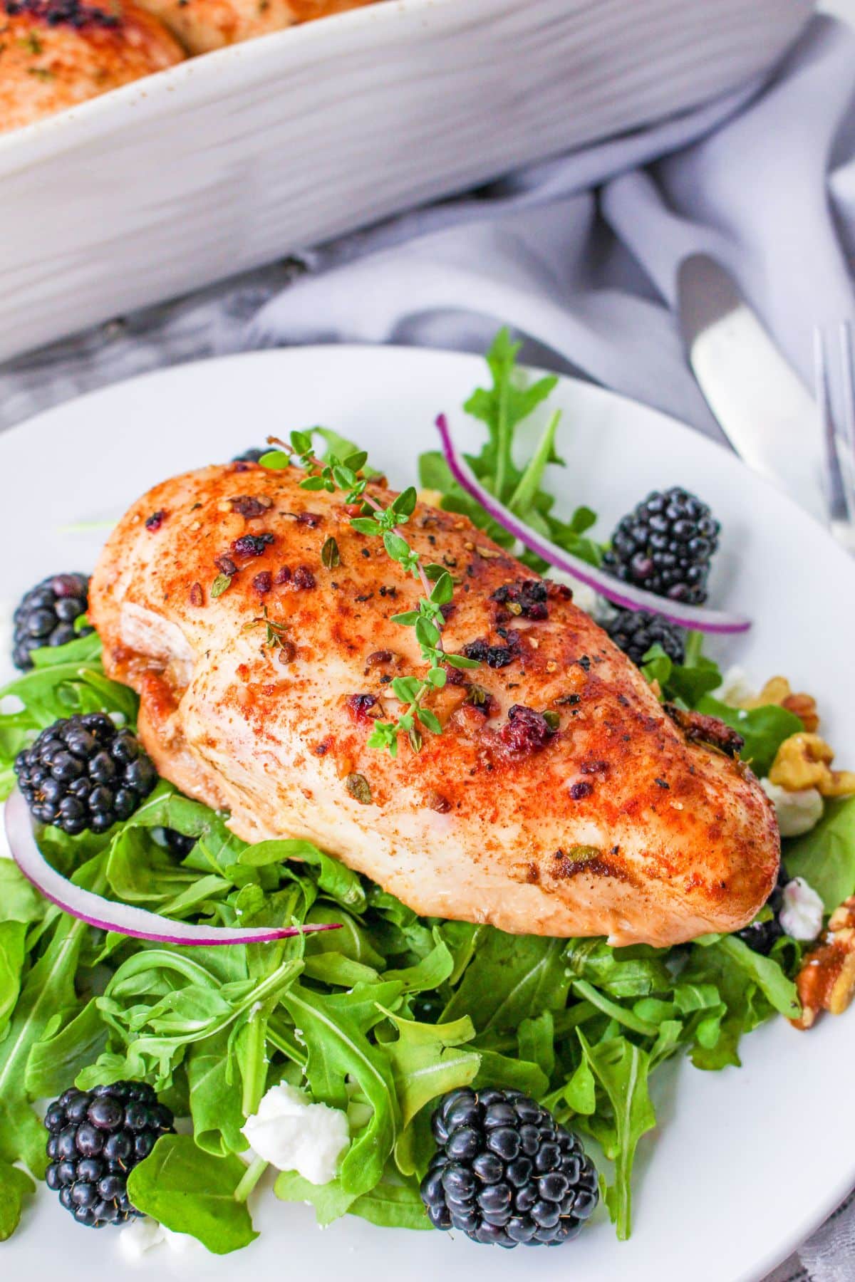 A baked chicken breast with blackberry glaze on a bed of lettuce. 