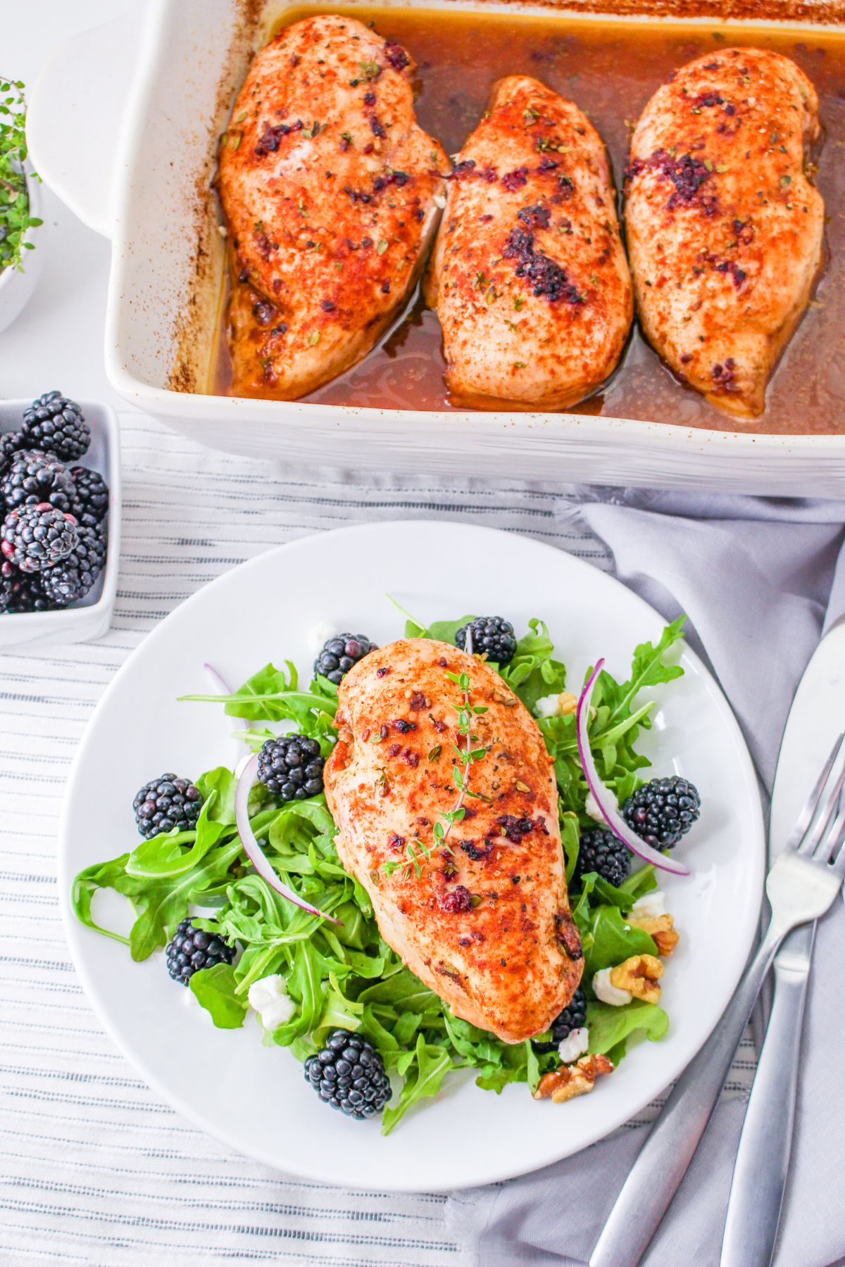 A baked chicken breast with blackberry glaze on a bed of lettuce.