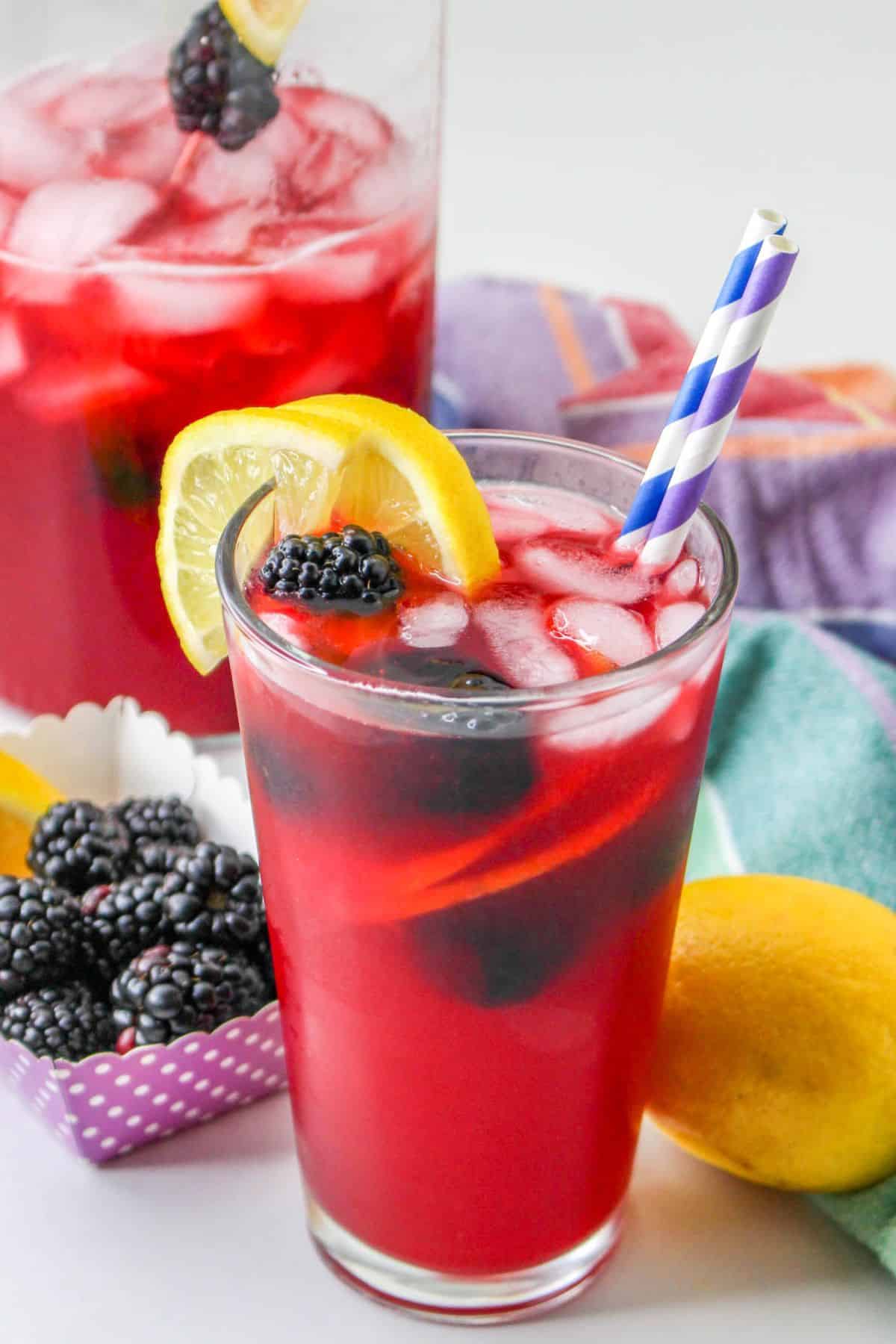 Blackberry lemonade with a slice of lemon and blackberry in a glass with ice. 