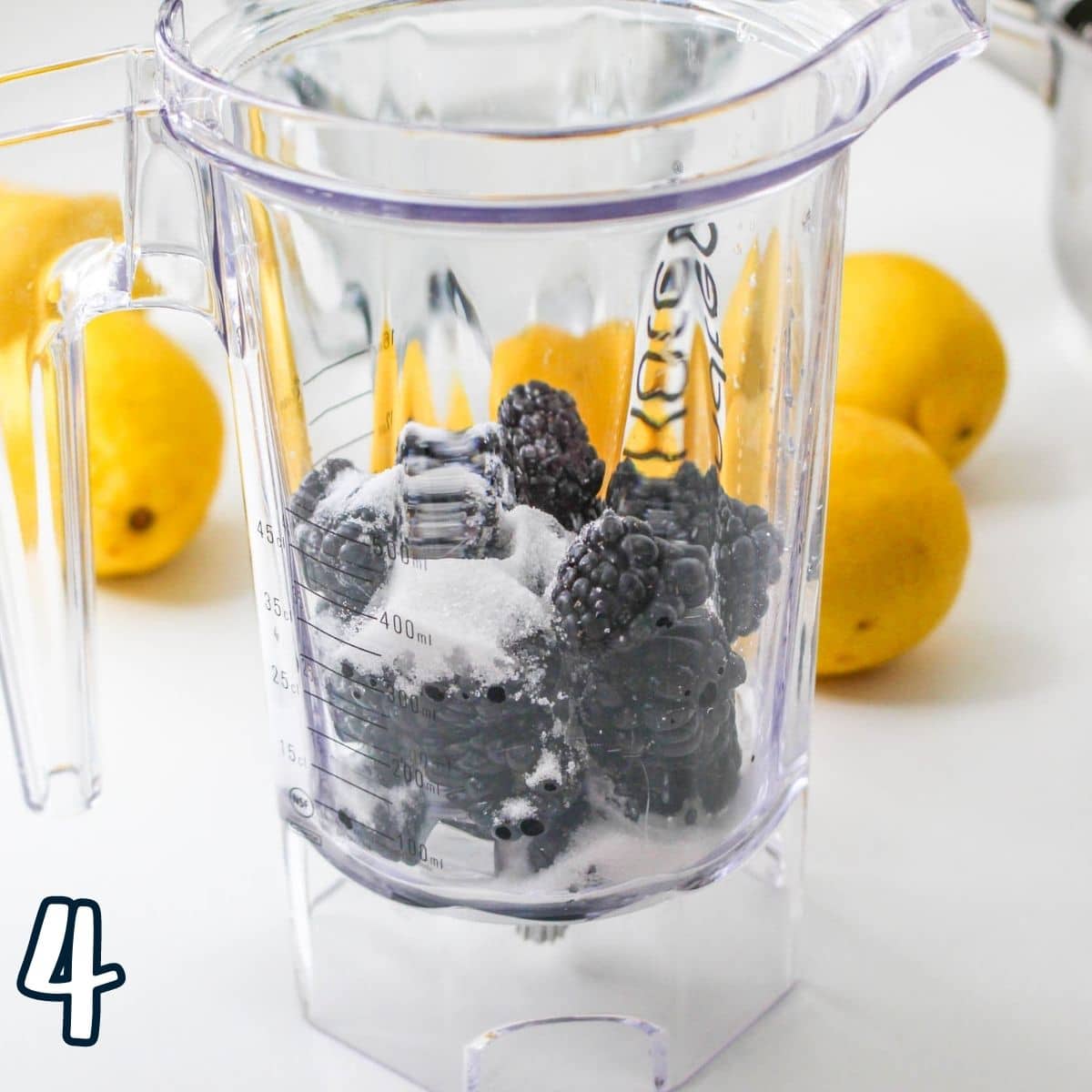 Blackberries and sugar in a blender pitcher. 
