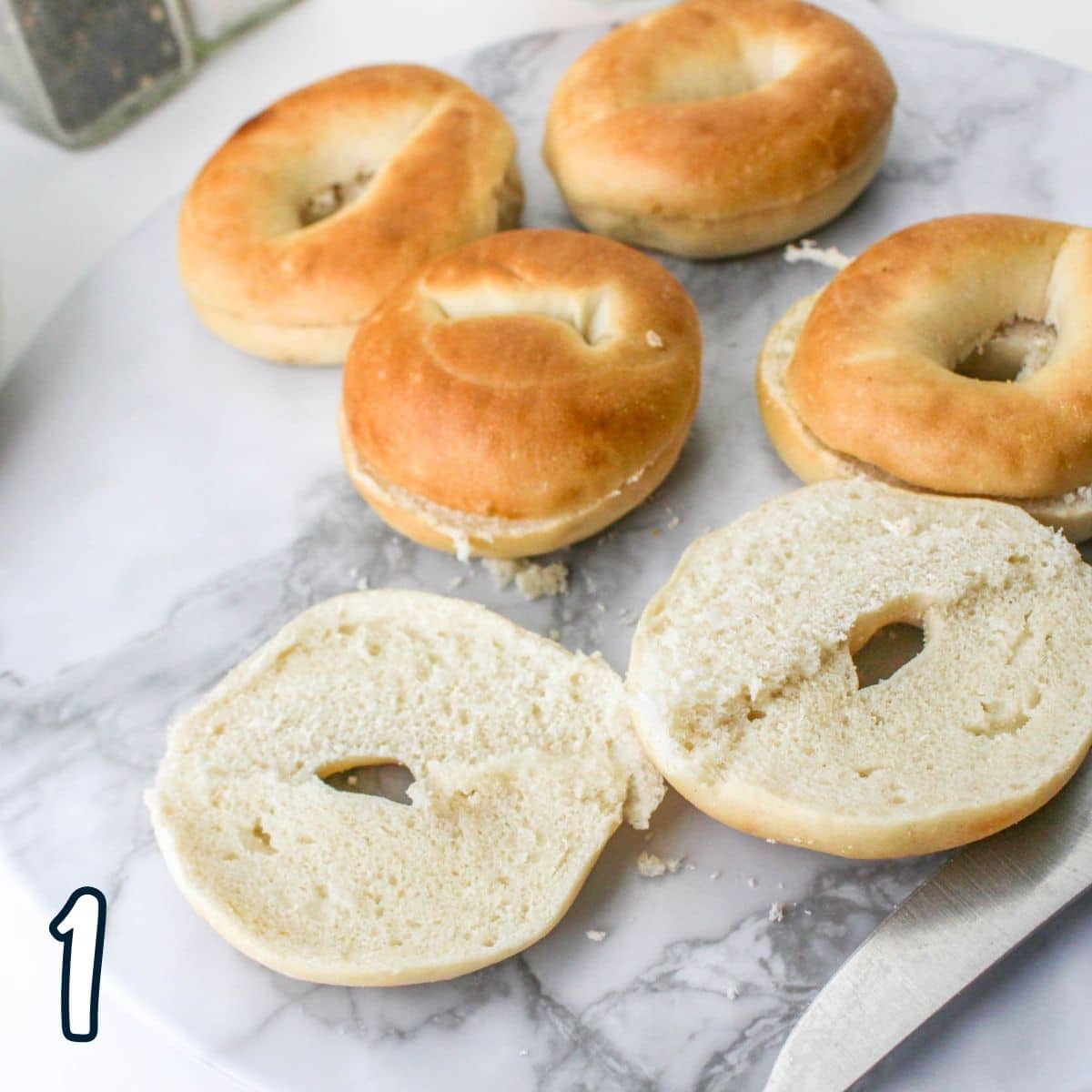 Mini bagels split in half on a marble background. 