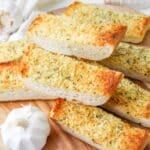 Toasted garlic bread slices on a wood cutting board.