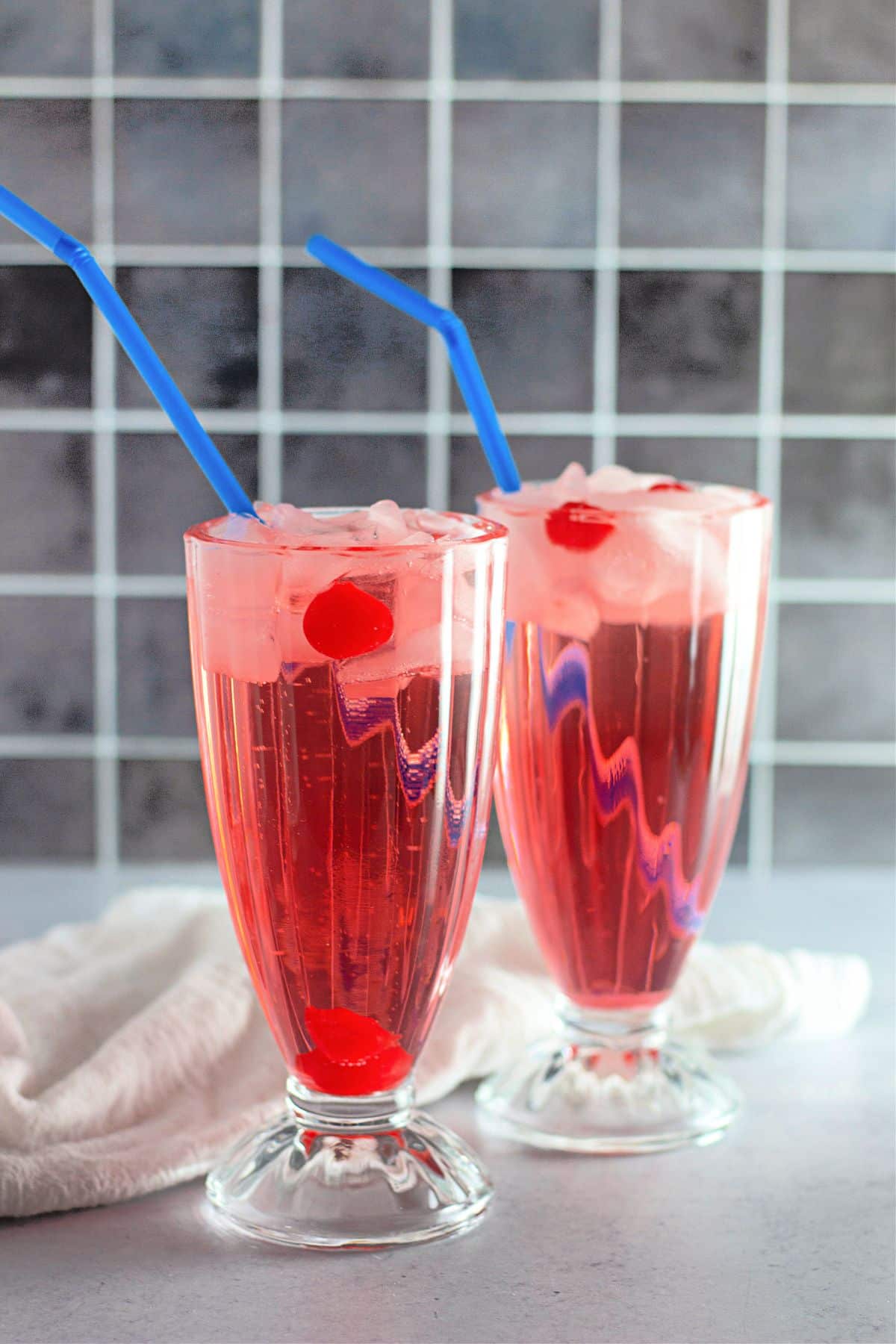 Two shirley temple drinks in clear glasses with ice.