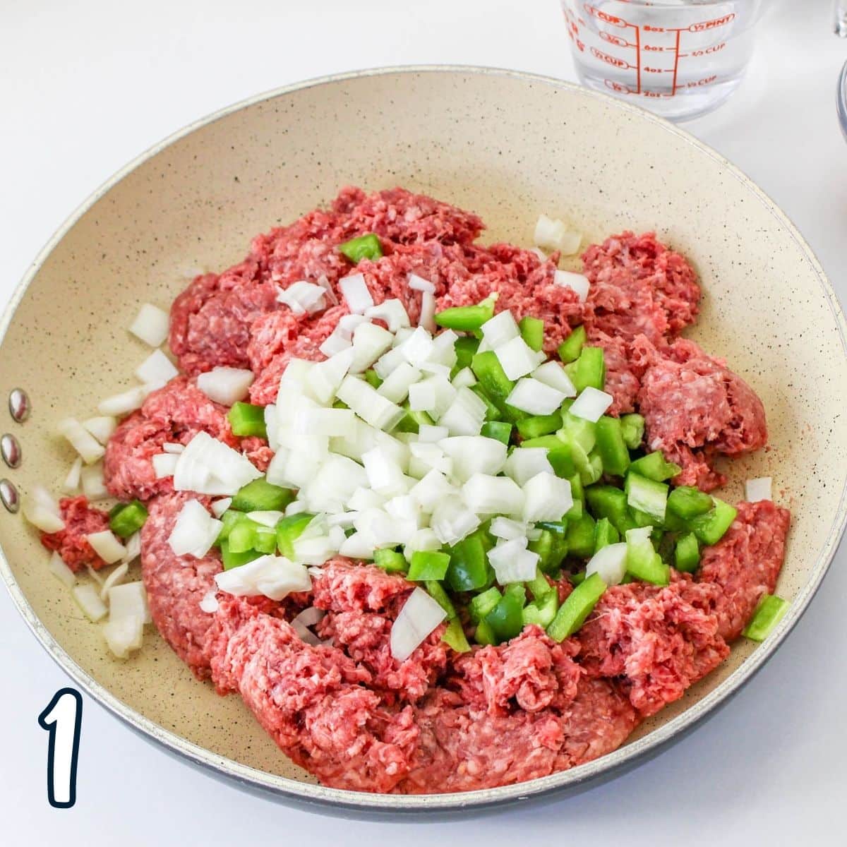 Ground beef, green pepper, and onion in a skillet.