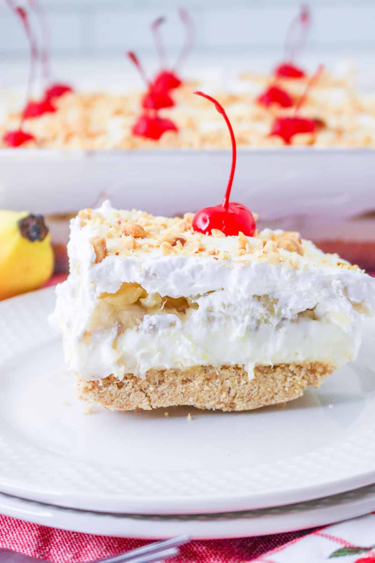 A square of banana split cake on a white plate.