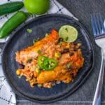 Baked chicken strips with beans and rice on a black plate.