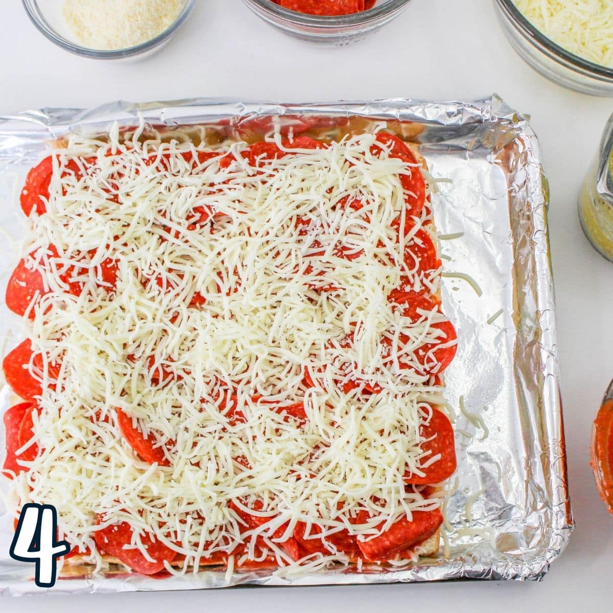 Another layer cheese being laid while making pizza sliders. 