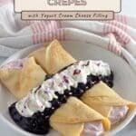 Three Blueberry Crepes with yogurt filling, topped with whipped cream and a luscious blueberry sauce, served on a white plate.