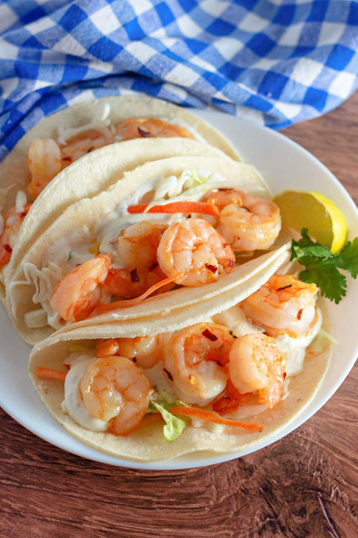 Corn tortillas filled with slaw and shrimp on a plate. 