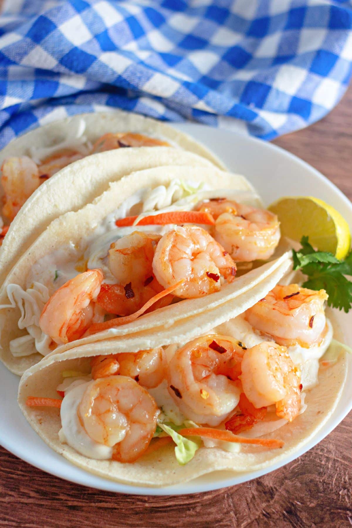 Corn tortillas filled with slaw and shrimp on a plate.