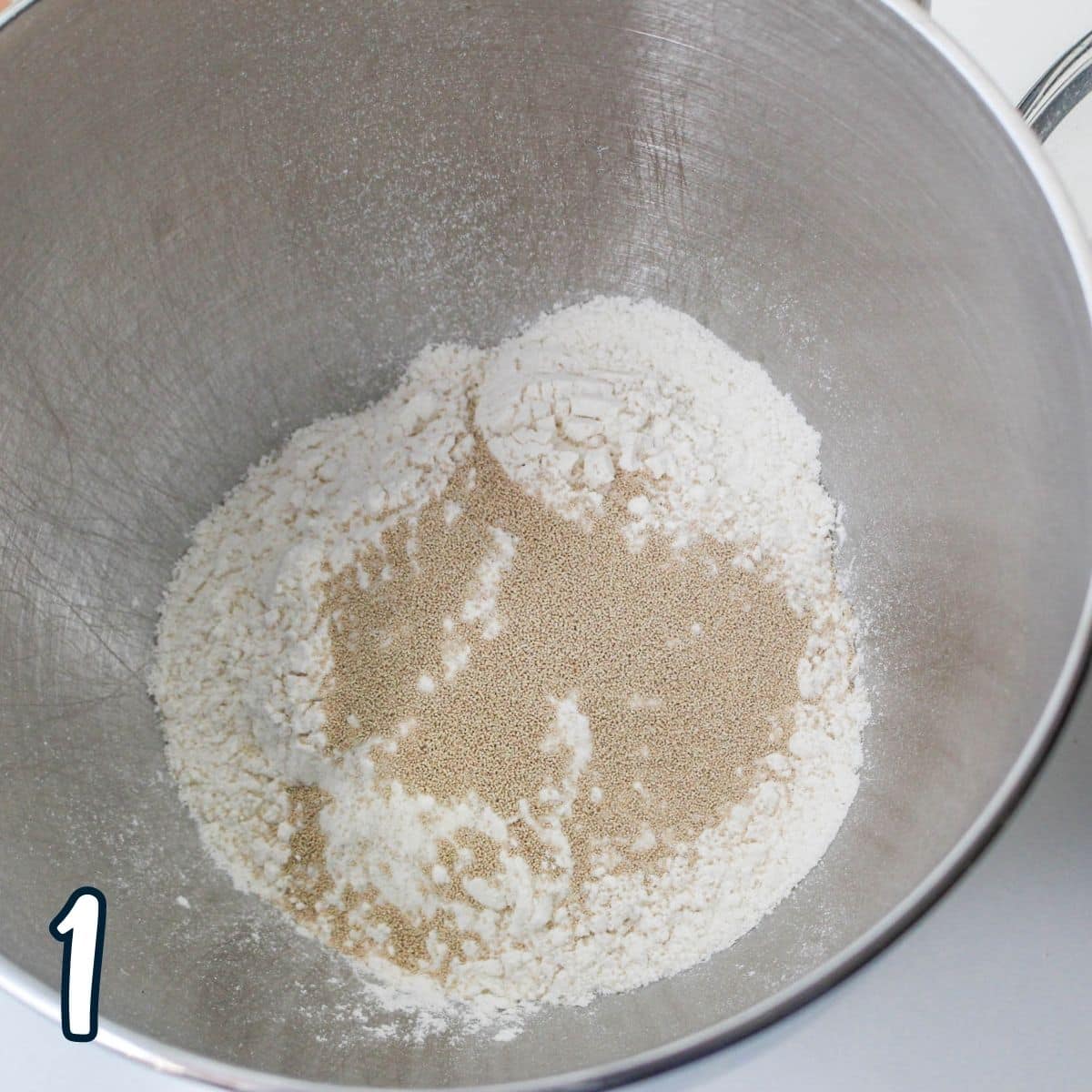 Flour and yeast in a metal mixing bowl.