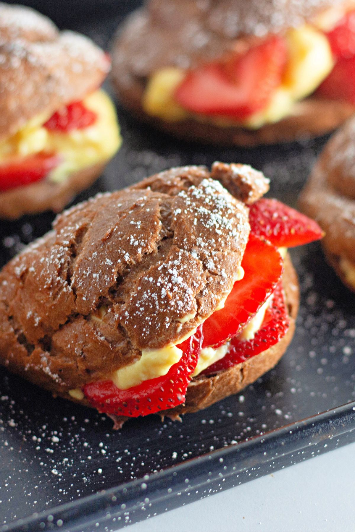 A chocolate cream puff filled with pudding and strawberries.