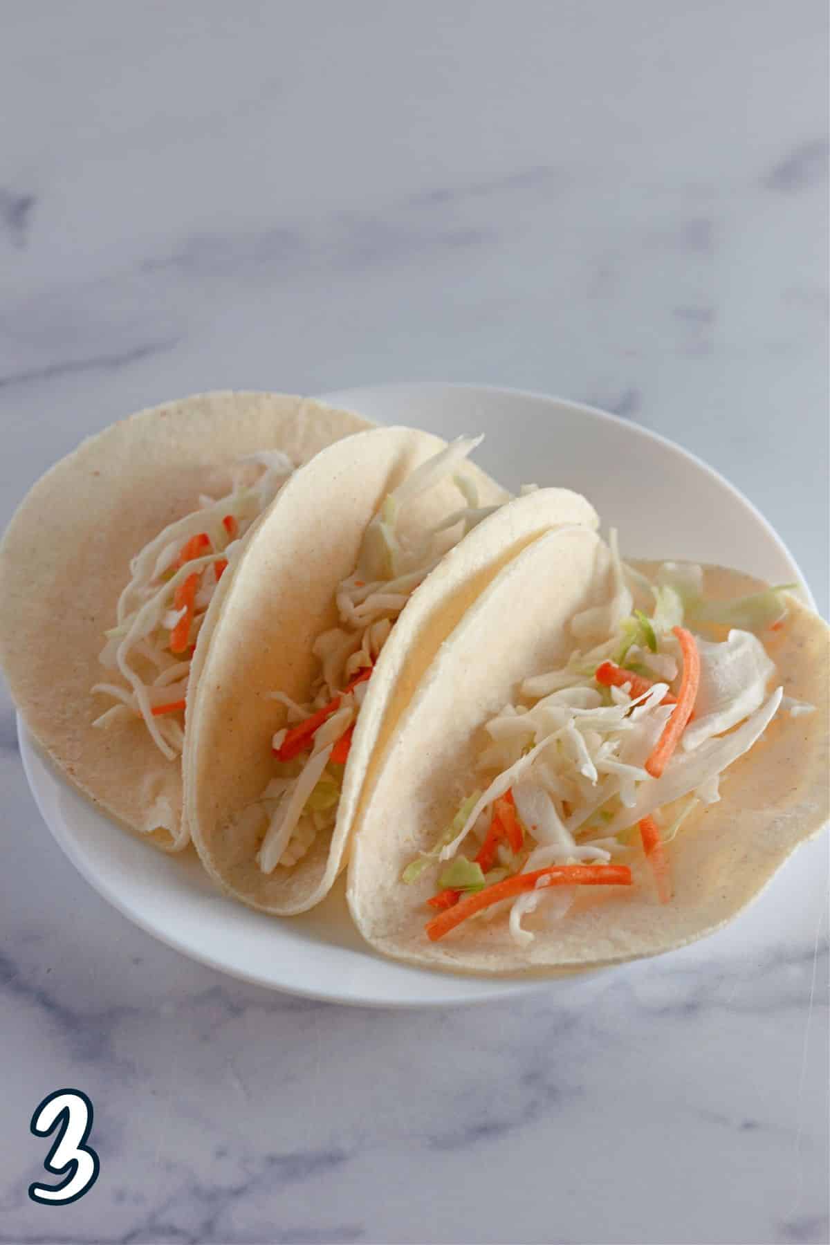 Cabbage slaw placed into corn taco shells.
