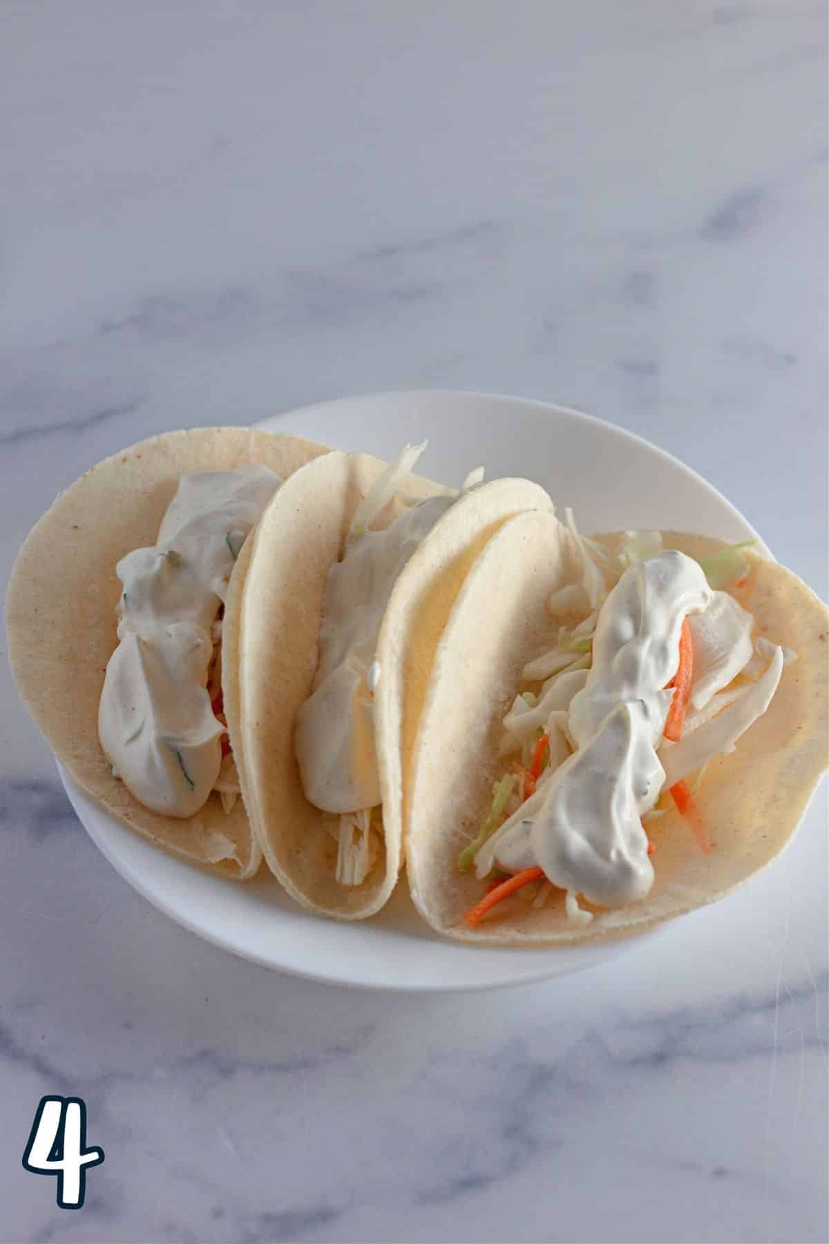 Sour cream cilantro sauce poured over shredded cabbage in a taco shell.