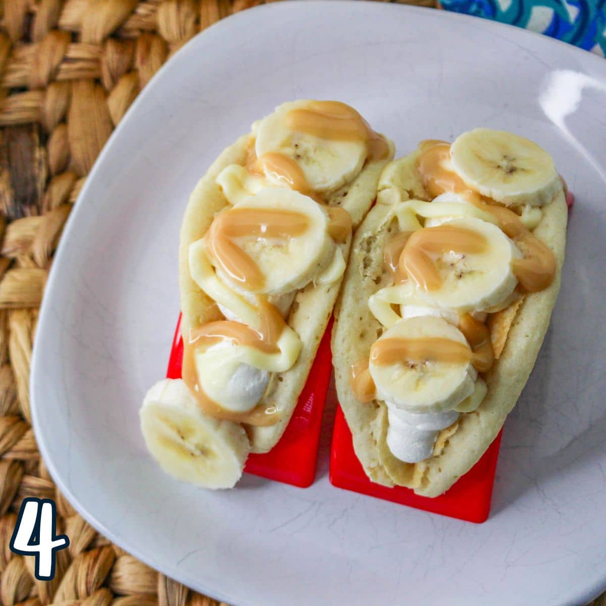 Pancake tacos filled with cheesecake mousse and sliced bananas with caramel sauce in red taco holders. 