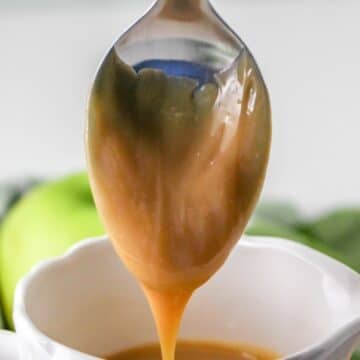 Dulce de Leche dripping from a spoon over a white cup.