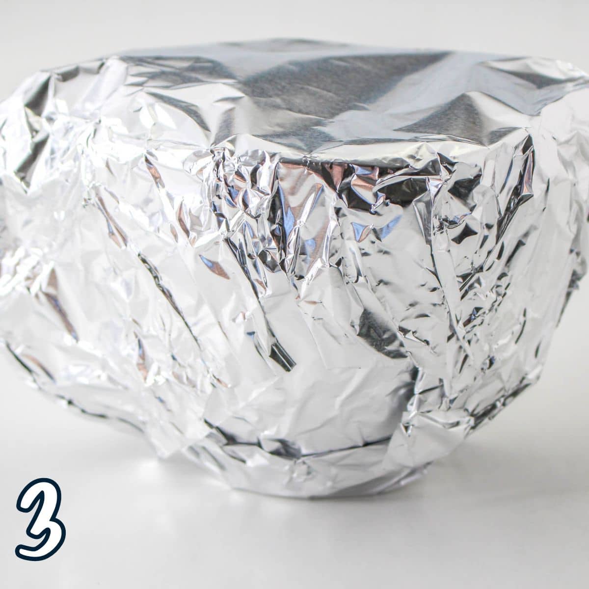 Foil completely covering a bowl filled with sweetened condensed milk. 