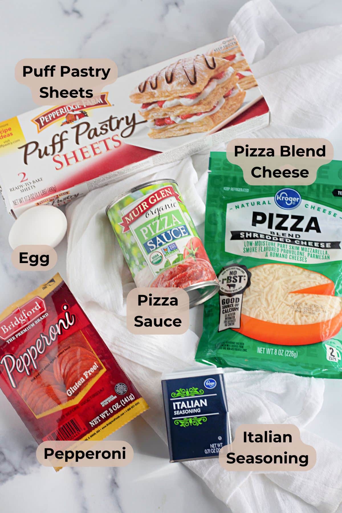 Puff pastry pizza pockets made with a flavorful pizza blend cheese, savory pepperoni, puff pastry, egg, pizza sauce, and Italian seasoning are displayed on a white cloth. These homemade pizza pockets offer a delicious twist on classic flavors in every bite.