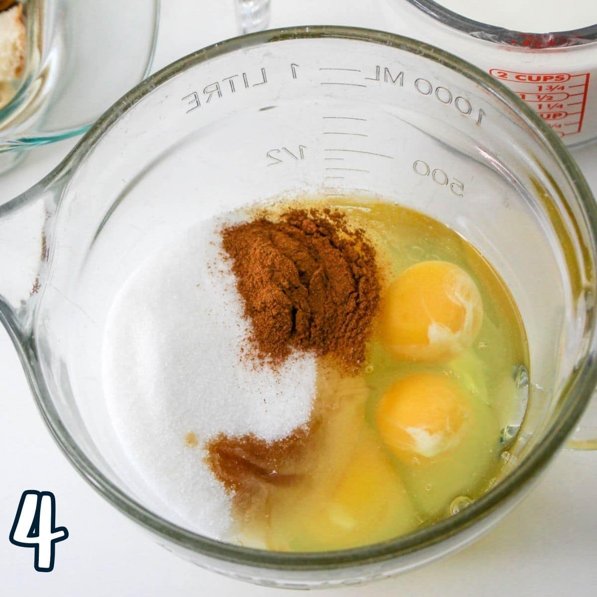 Eggs, milk, sugar, and cinnamon in a glass mixing bowl. 