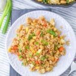 A white plate filled with cashew fried rice on a gray tablecloth.