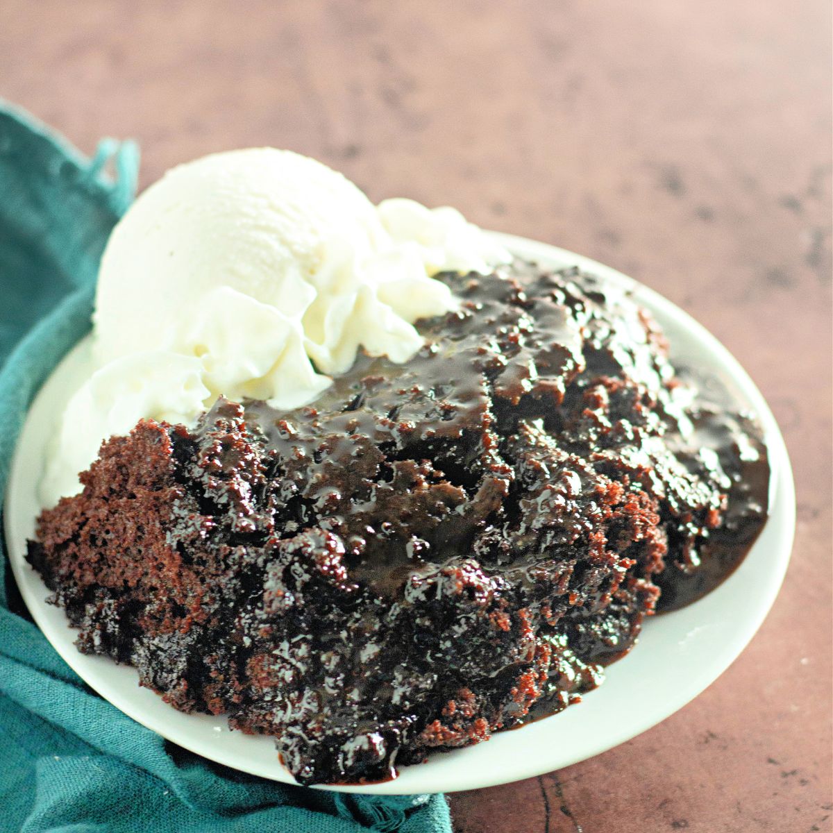 Chocolate lava cake on a white plate next to the dish with the remaining cake.