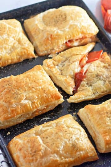 Golden brown puff pastry pockets on a black cookie sheet.