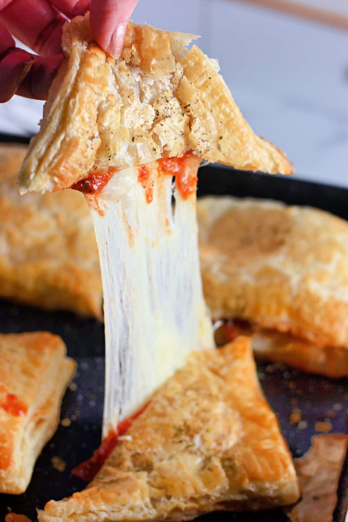 A homemade pizza pocket being separated with a huge cheese pull. 
