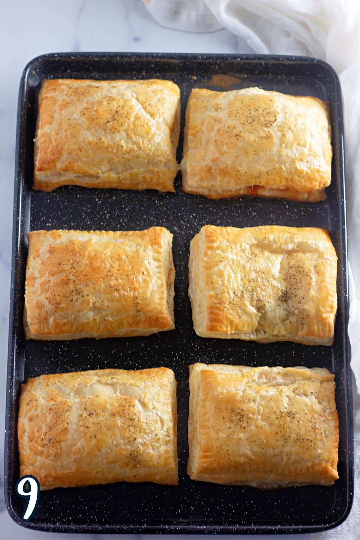 Six golden brown puff pastry pockets that have just been baked. 