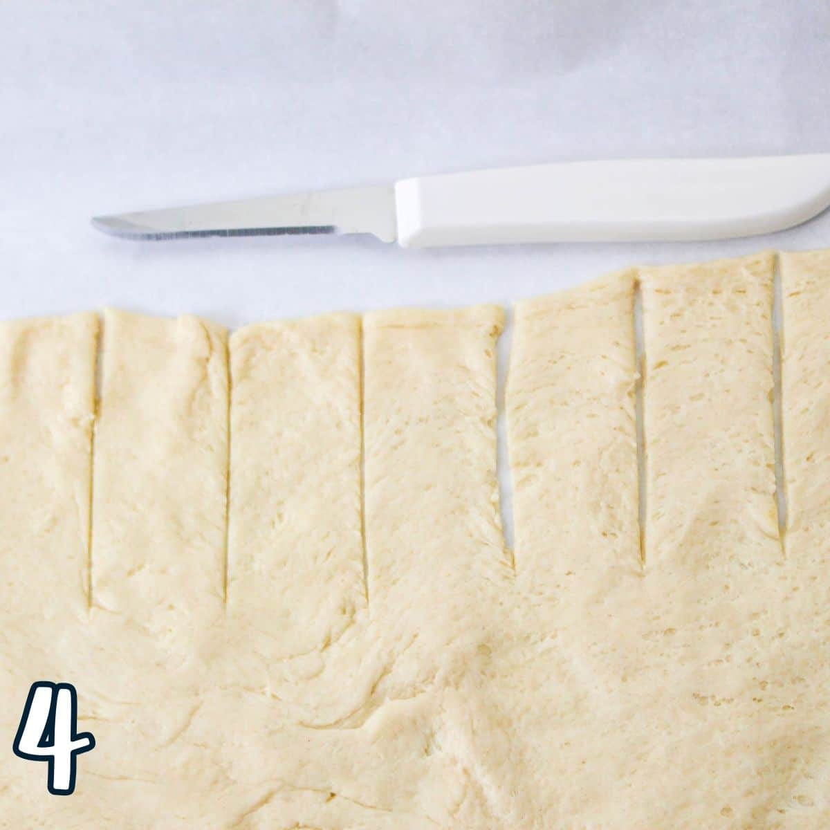 Slits cut into a piece of crescent roll dough. 