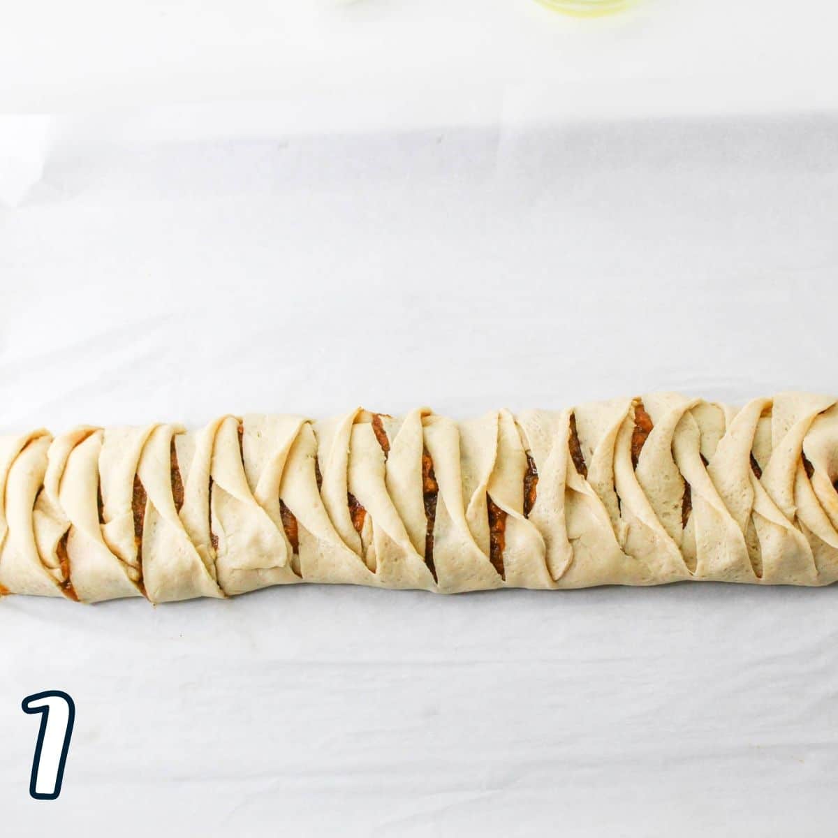 A breakfast pastry braid on a piece of parchment paper. 