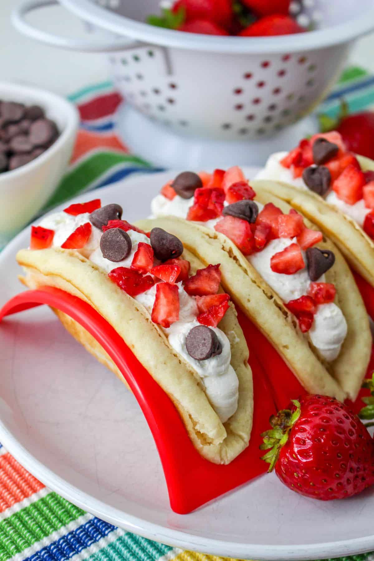 Pancakes filled with cheesecake mousse, strawberries, and chocolate chips in a red taco holder. 