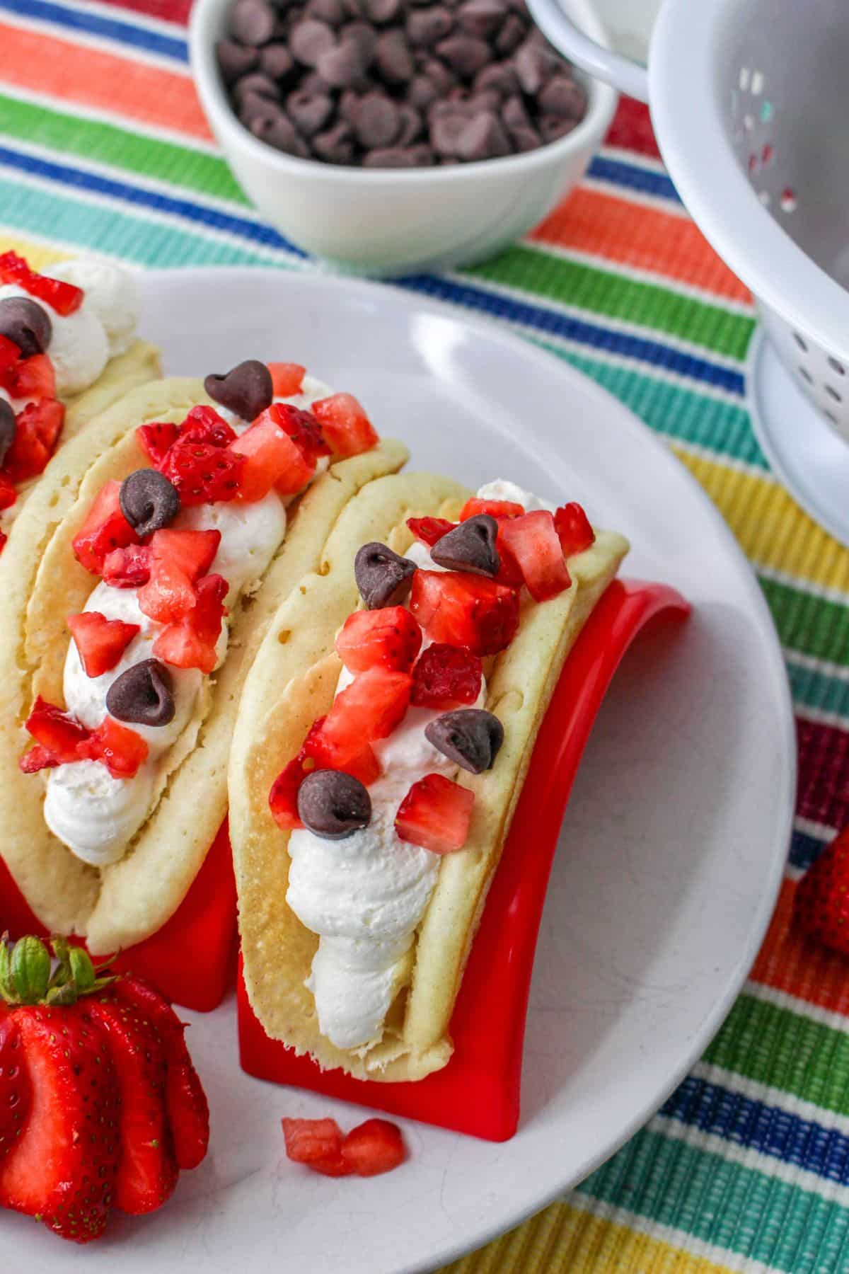 Pancakes filled with cheesecake mousse, strawberries, and chocolate chips in a red taco holder.