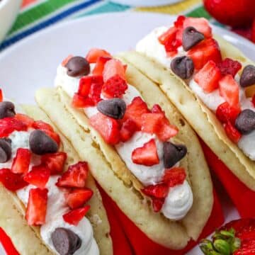 Pancakes filled with cheesecake mousse, strawberries, and chocolate chips in a red taco holder.