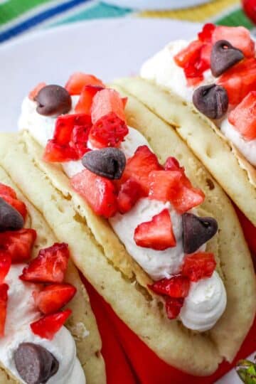 Pancakes filled with cheesecake mousse, strawberries, and chocolate chips in a red taco holder.