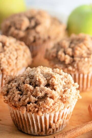 Apple cinnamon muffins on a cutting board with cinnamon sticks.
