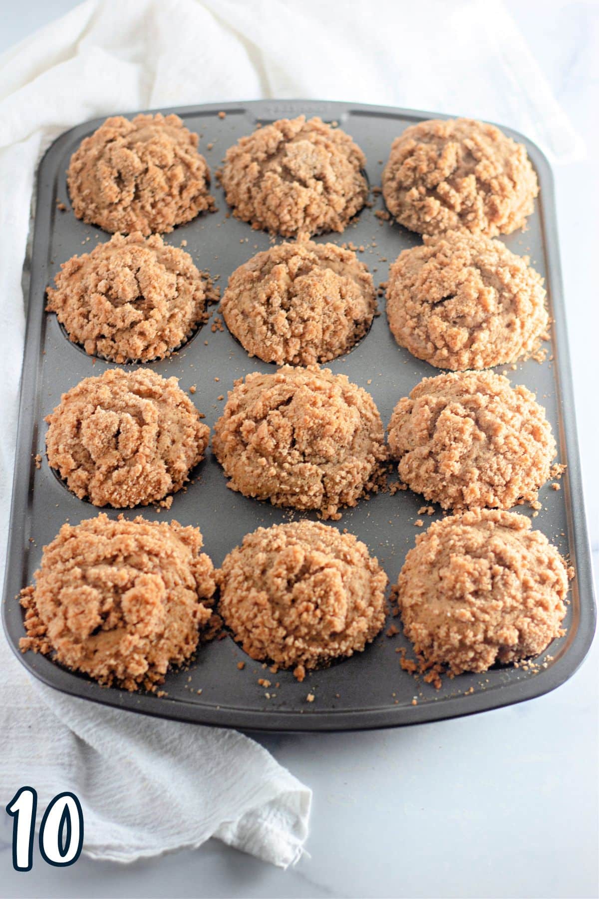 A muffin tin with just baked apple crumb muffins. 